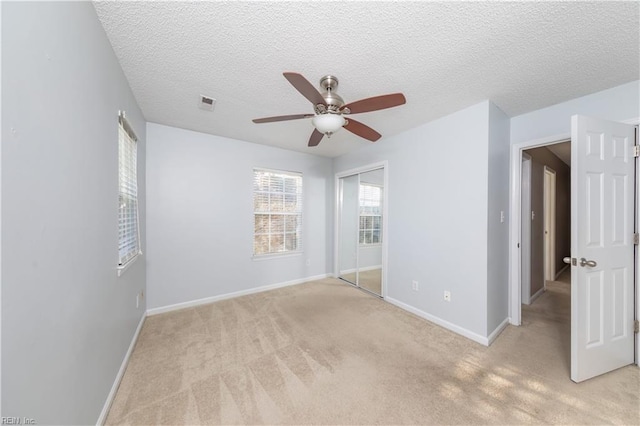 empty room featuring ceiling fan, light colored carpet, and a textured ceiling