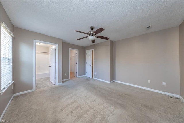 interior space featuring ceiling fan, light colored carpet, and a textured ceiling