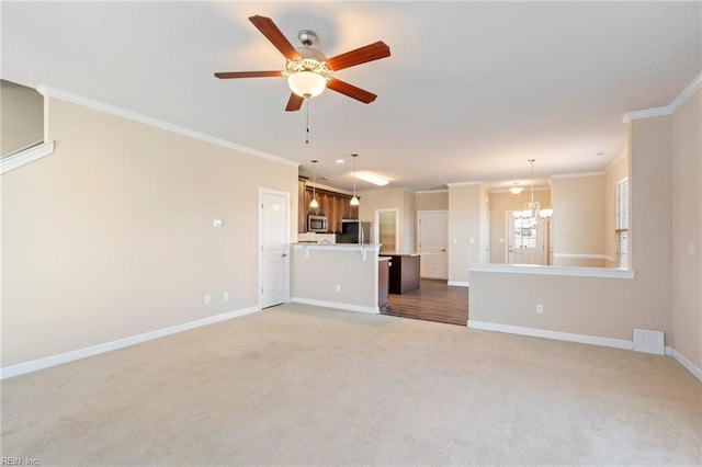 unfurnished living room featuring carpet, ceiling fan with notable chandelier, and ornamental molding