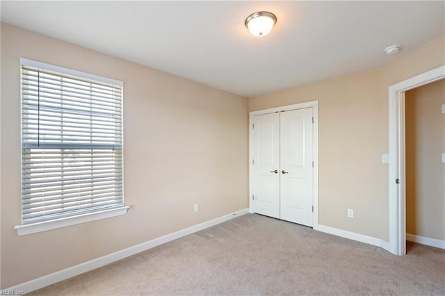 unfurnished bedroom with light carpet and a closet