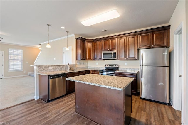 kitchen with pendant lighting, crown molding, sink, and stainless steel appliances