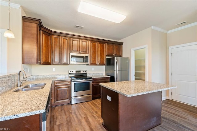 kitchen with pendant lighting, sink, light stone countertops, and stainless steel appliances