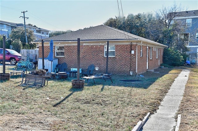 view of side of property with a lawn and a fire pit