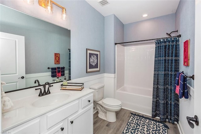 full bathroom featuring hardwood / wood-style floors, vanity, shower / tub combo, and toilet