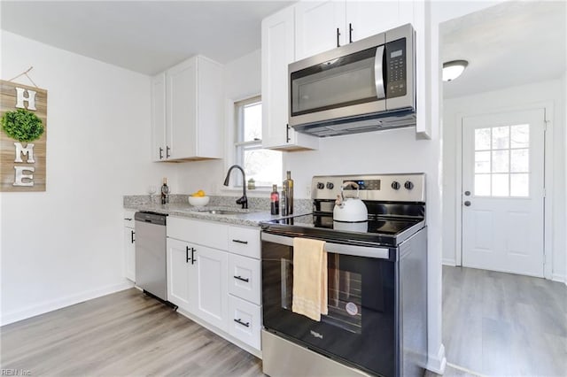 kitchen featuring light stone counters, sink, white cabinetry, and stainless steel appliances