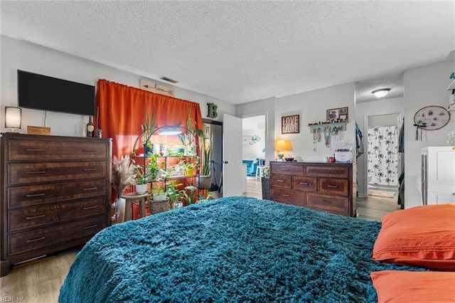 bedroom with a textured ceiling and light hardwood / wood-style floors