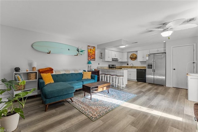 living room with ceiling fan, sink, and light wood-type flooring