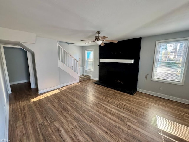 unfurnished living room with hardwood / wood-style floors, a large fireplace, and a healthy amount of sunlight