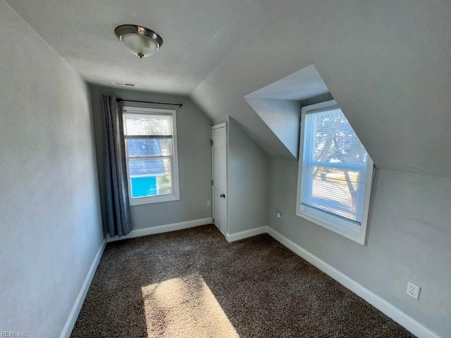 additional living space with dark carpet and vaulted ceiling