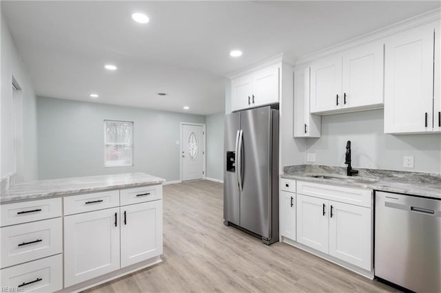 kitchen featuring light stone countertops, white cabinetry, sink, appliances with stainless steel finishes, and light wood-type flooring