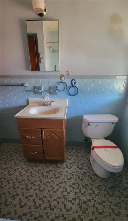 bathroom featuring vanity, toilet, and tile walls