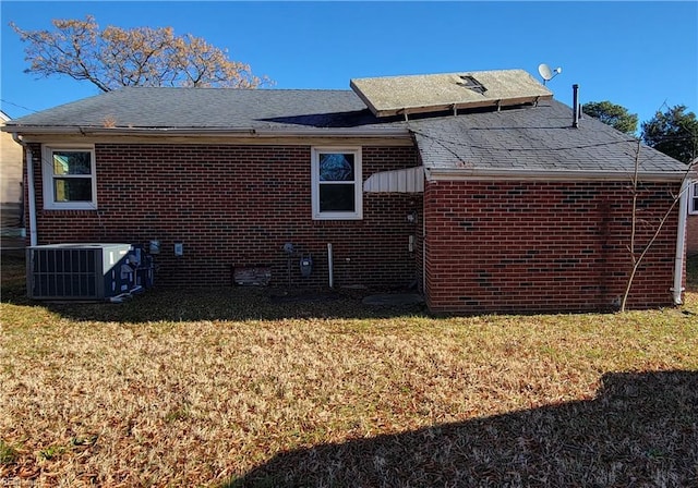 back of property with central air condition unit and a lawn