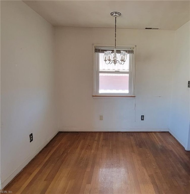 unfurnished dining area with hardwood / wood-style floors and a chandelier