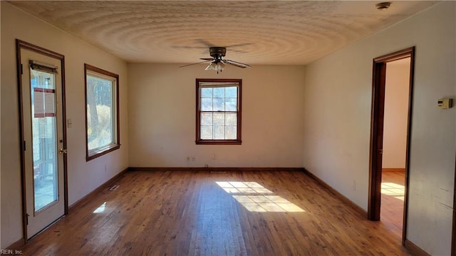 empty room with ceiling fan, light hardwood / wood-style flooring, and a textured ceiling