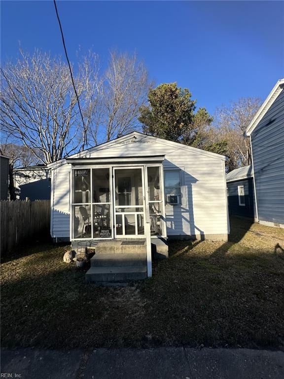 rear view of property featuring a sunroom, cooling unit, and a yard