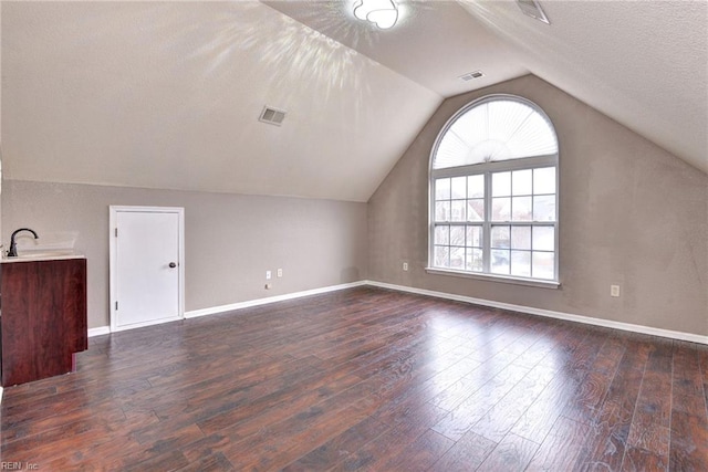 bonus room with a textured ceiling, sink, dark wood-type flooring, and vaulted ceiling