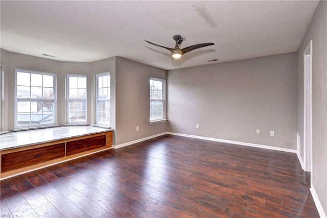 empty room featuring a textured ceiling, ceiling fan, and dark wood-type flooring