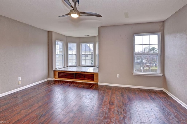 unfurnished room featuring a wealth of natural light, dark wood-type flooring, and ceiling fan