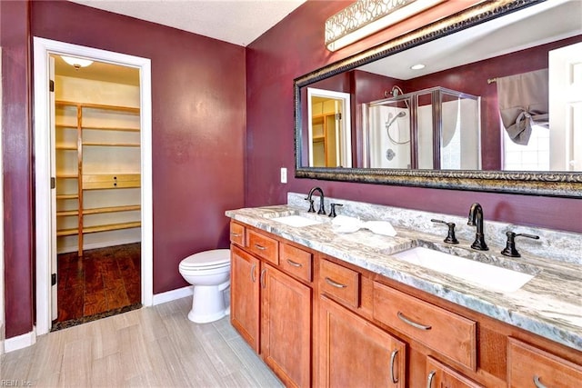 bathroom featuring toilet, a shower with door, vanity, and hardwood / wood-style flooring