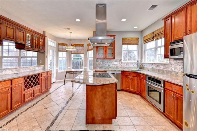 kitchen with appliances with stainless steel finishes, island range hood, a kitchen island, and light tile patterned flooring