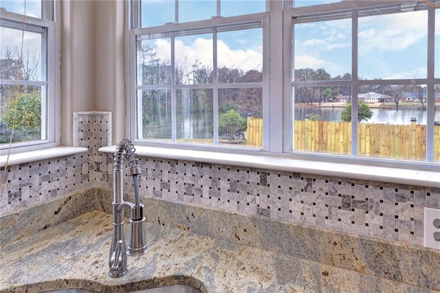 interior details featuring light stone countertops, a water view, and sink