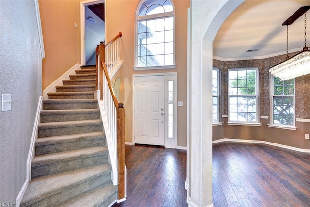 foyer with dark hardwood / wood-style floors, an inviting chandelier, and ornamental molding