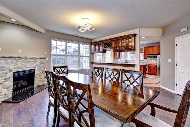 dining area with a fireplace, hardwood / wood-style floors, and a notable chandelier