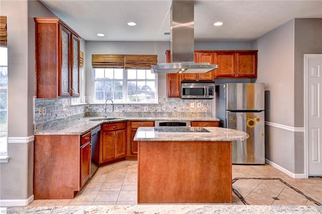 kitchen with light stone countertops, appliances with stainless steel finishes, a kitchen island, and sink