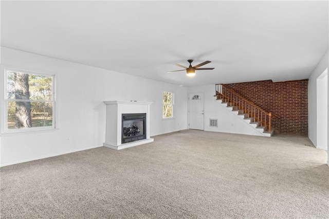 unfurnished living room with plenty of natural light, ceiling fan, and carpet floors