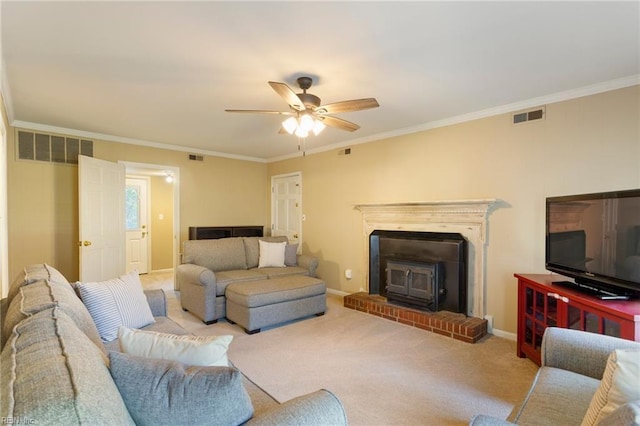 carpeted living room with a wood stove, ceiling fan, and crown molding