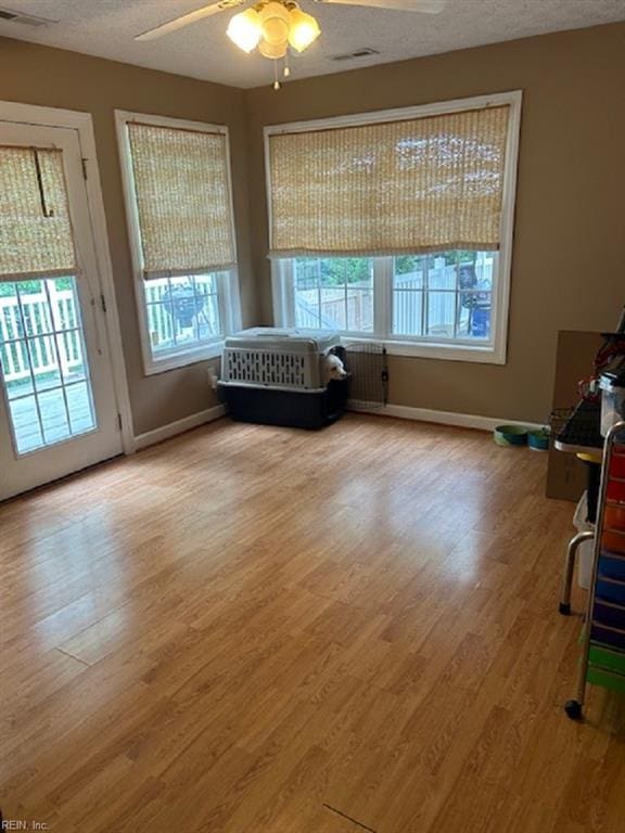 unfurnished room featuring a wealth of natural light, ceiling fan, and a textured ceiling