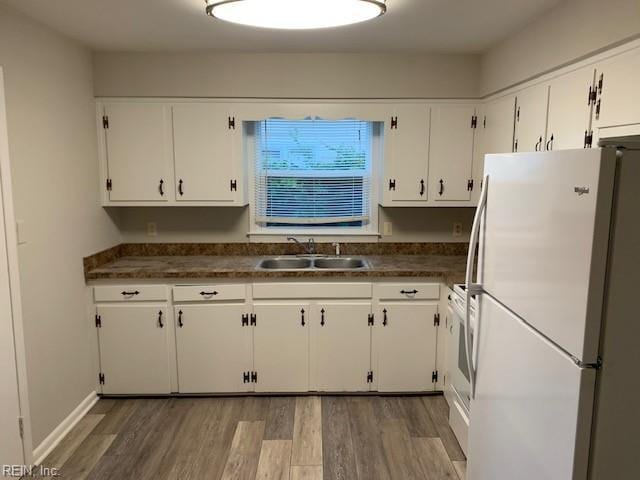 kitchen with range, white refrigerator, sink, dark hardwood / wood-style flooring, and white cabinetry