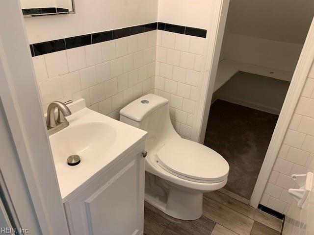 bathroom featuring vanity, tile walls, and toilet