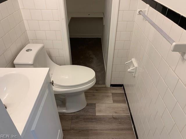 bathroom featuring vanity, wood-type flooring, tile walls, and toilet