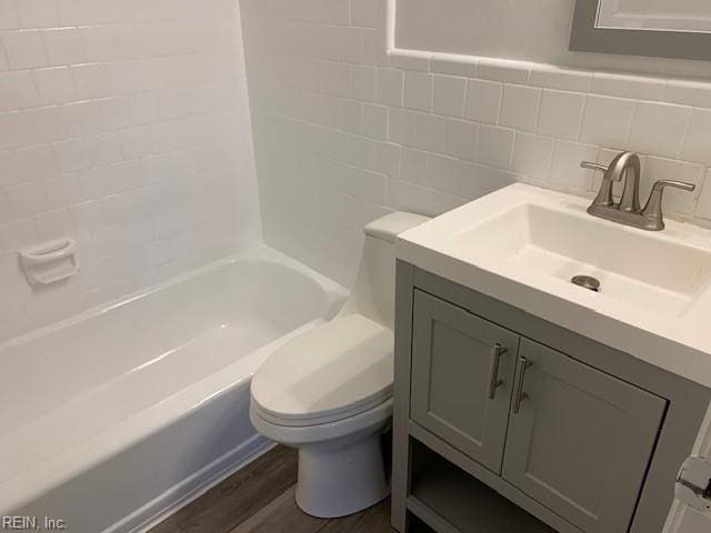 full bathroom with wood-type flooring, toilet, shower / washtub combination, vanity, and tile walls