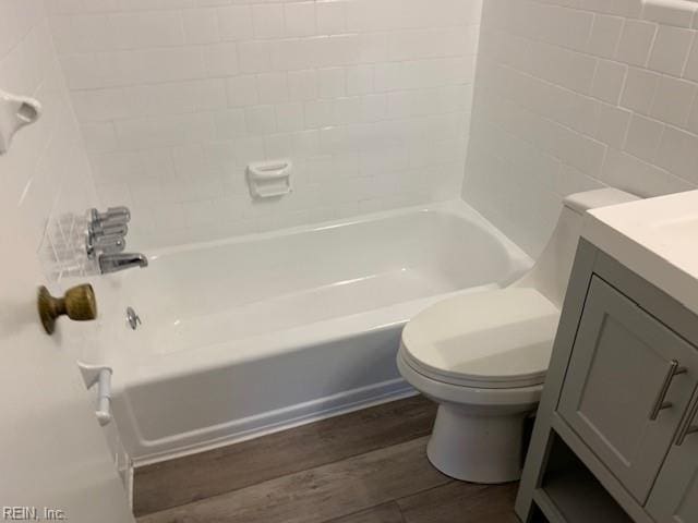 full bathroom featuring vanity, wood-type flooring, tile walls, washtub / shower combination, and toilet