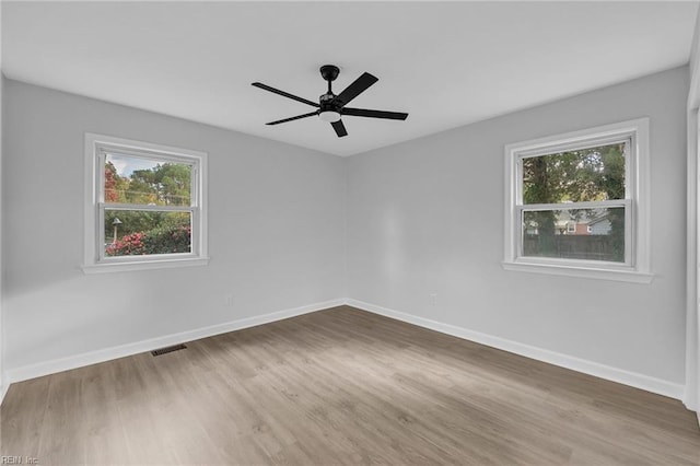 empty room with wood-type flooring, a wealth of natural light, and ceiling fan