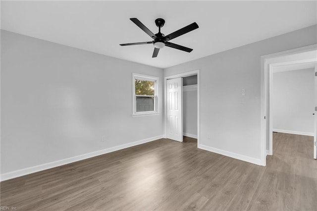 unfurnished bedroom featuring ceiling fan, a closet, and wood-type flooring