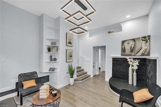 living area featuring light wood-type flooring, built in features, and a notable chandelier