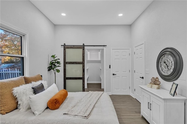 bedroom with a barn door and dark hardwood / wood-style floors