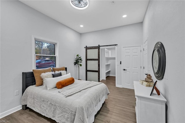 bedroom featuring a barn door and dark wood-type flooring