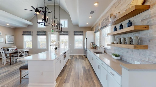 kitchen with white cabinets, sink, decorative backsplash, light wood-type flooring, and decorative light fixtures