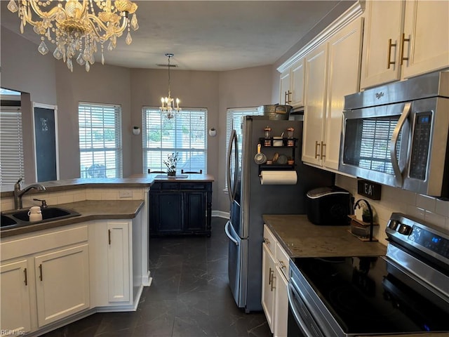 kitchen with white cabinetry, sink, an inviting chandelier, decorative light fixtures, and appliances with stainless steel finishes