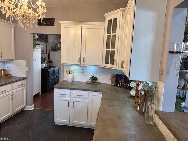 kitchen featuring backsplash, white cabinets, a chandelier, and decorative light fixtures