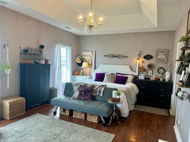 bedroom with a tray ceiling, dark hardwood / wood-style floors, and a notable chandelier