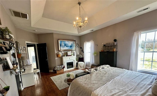 bedroom featuring a chandelier, dark hardwood / wood-style flooring, and a raised ceiling