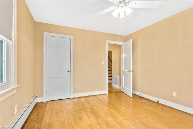 unfurnished bedroom featuring ceiling fan, a baseboard radiator, and light hardwood / wood-style floors