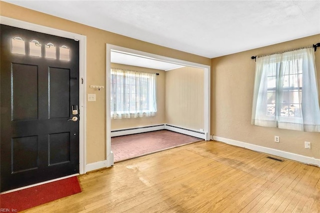 foyer entrance featuring light hardwood / wood-style floors, baseboard heating, and a wealth of natural light