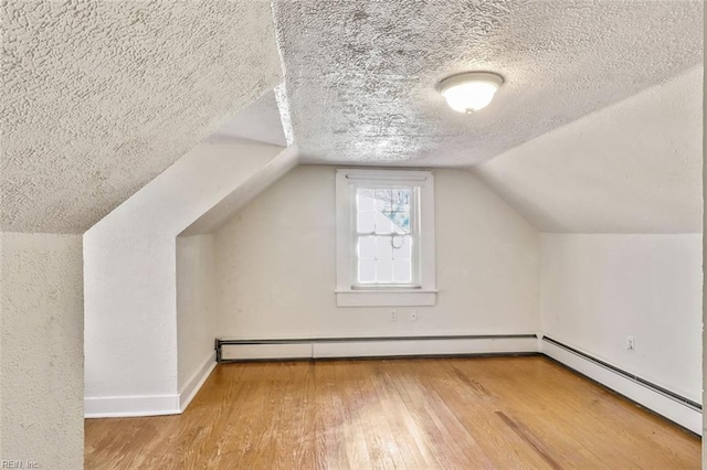 bonus room with wood-type flooring, lofted ceiling, a textured ceiling, and a baseboard heating unit