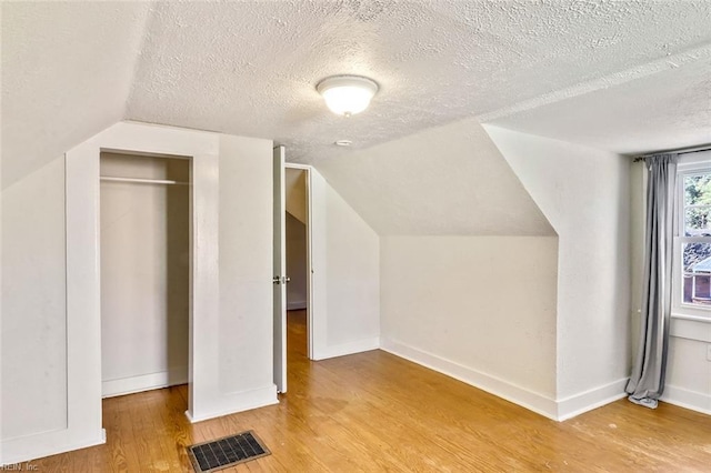 bonus room featuring a textured ceiling, vaulted ceiling, and hardwood / wood-style flooring